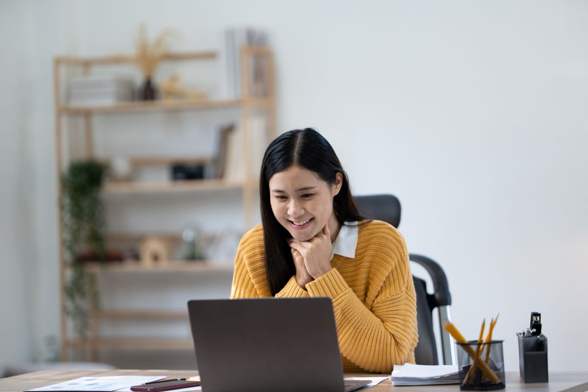 Happy university student, female, looking at her laptop.